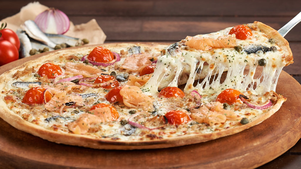 Fotografie culinară cu o felie de pizza Trenta Pescara Artigianale, în timp ce este ridicată de pe blat, cu mozzarella care se întinde.