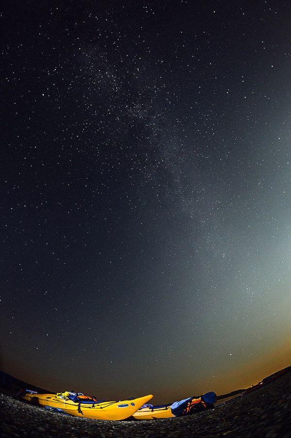 Fotografie cu două caiace la malul Dunării noaptea, cu Calea Lactee vizibilă.